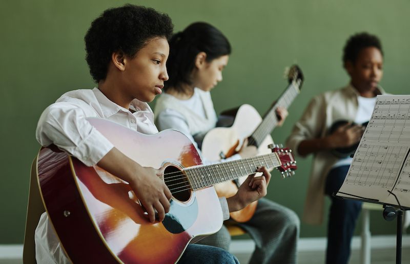 Students playing acoustic guitars together in a group music lesson